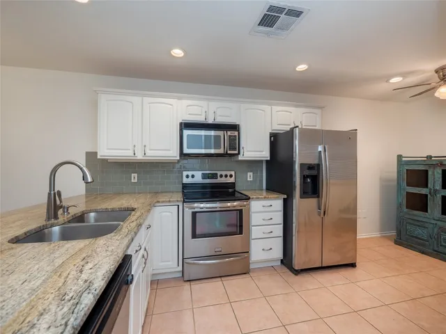 a kitchen with stainless steel appliances granite countertop a stove a sink and a microwave