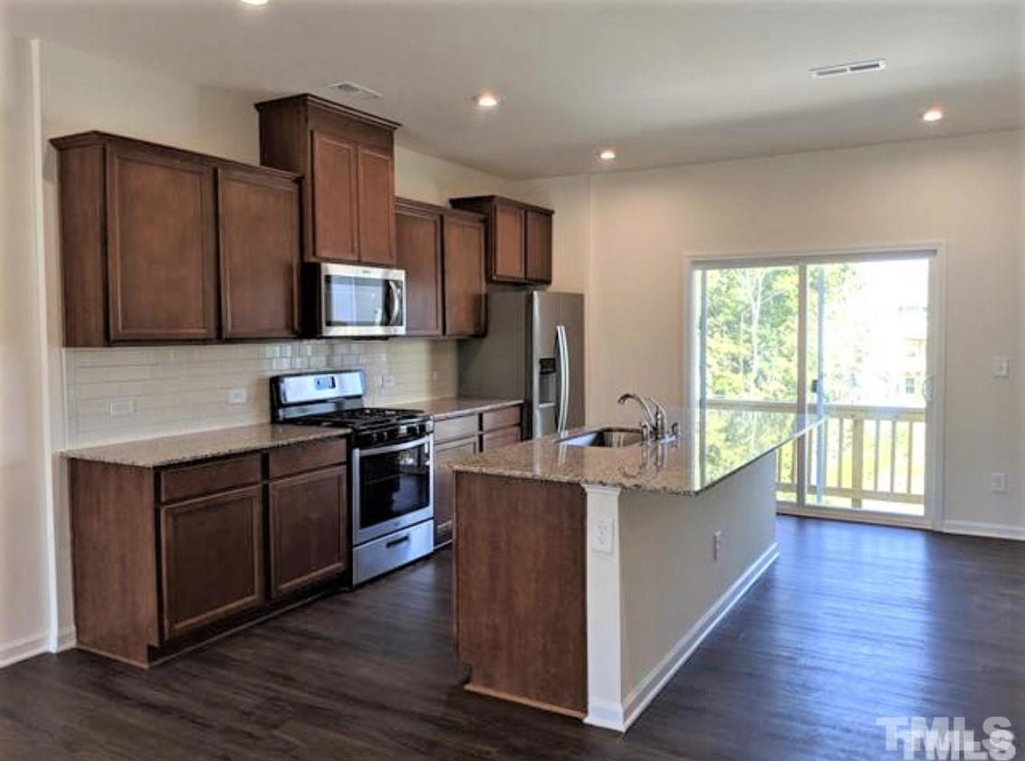 a kitchen with stainless steel appliances wooden floors and a window