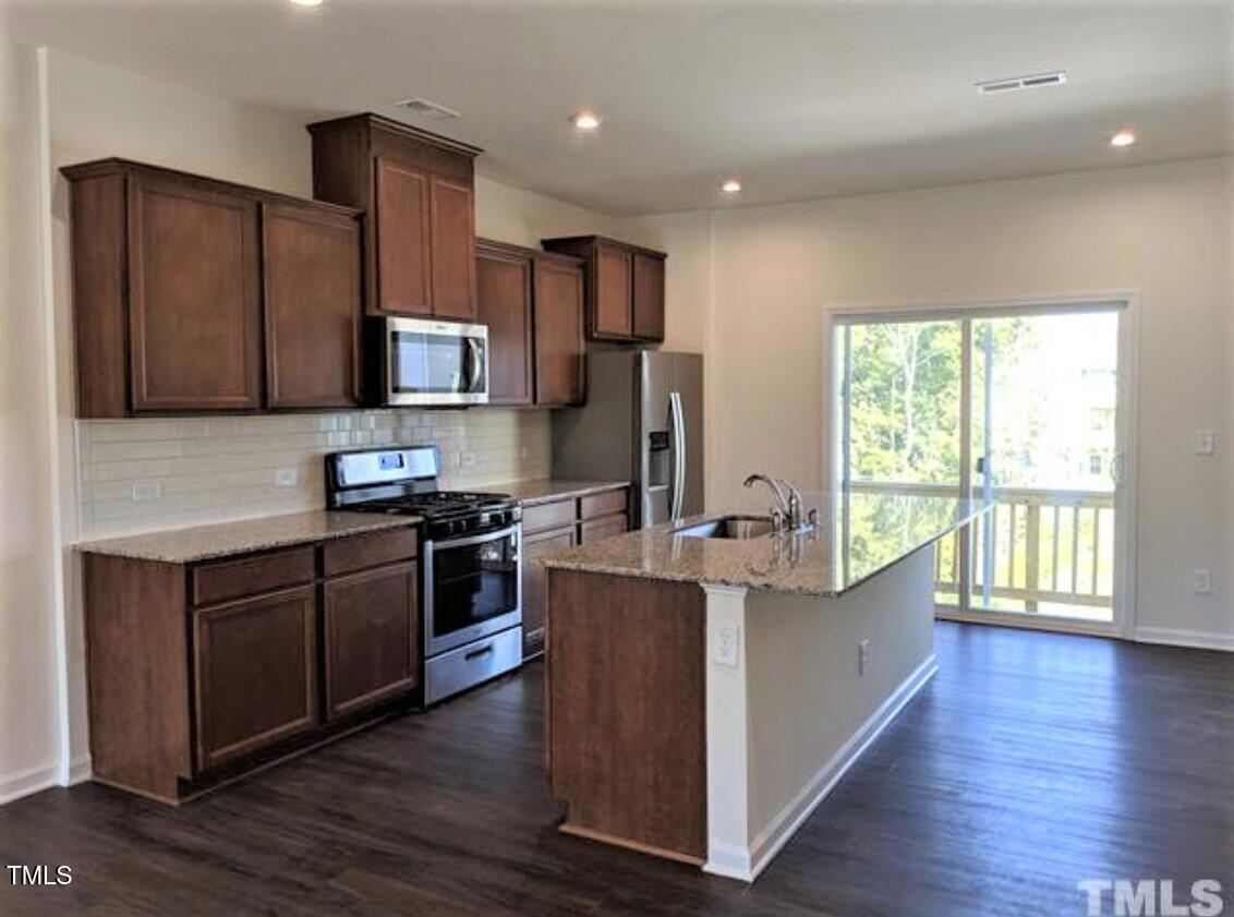 4121 Mahal Avenue Cary, NC 27519 - Photo 6 of 33 a kitchen with stainless steel appliances granite countertop a stove a sink and a refrigerator