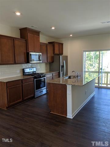 4121 Mahal Avenue Cary, NC 27519 - Photo 8 of 33 a kitchen with stainless steel appliances wooden floors and wooden cabinets