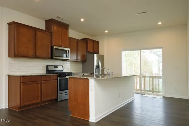 a kitchen with stainless steel appliances granite countertop a stove a sink a refrigerator a microwave a sink and cabinets