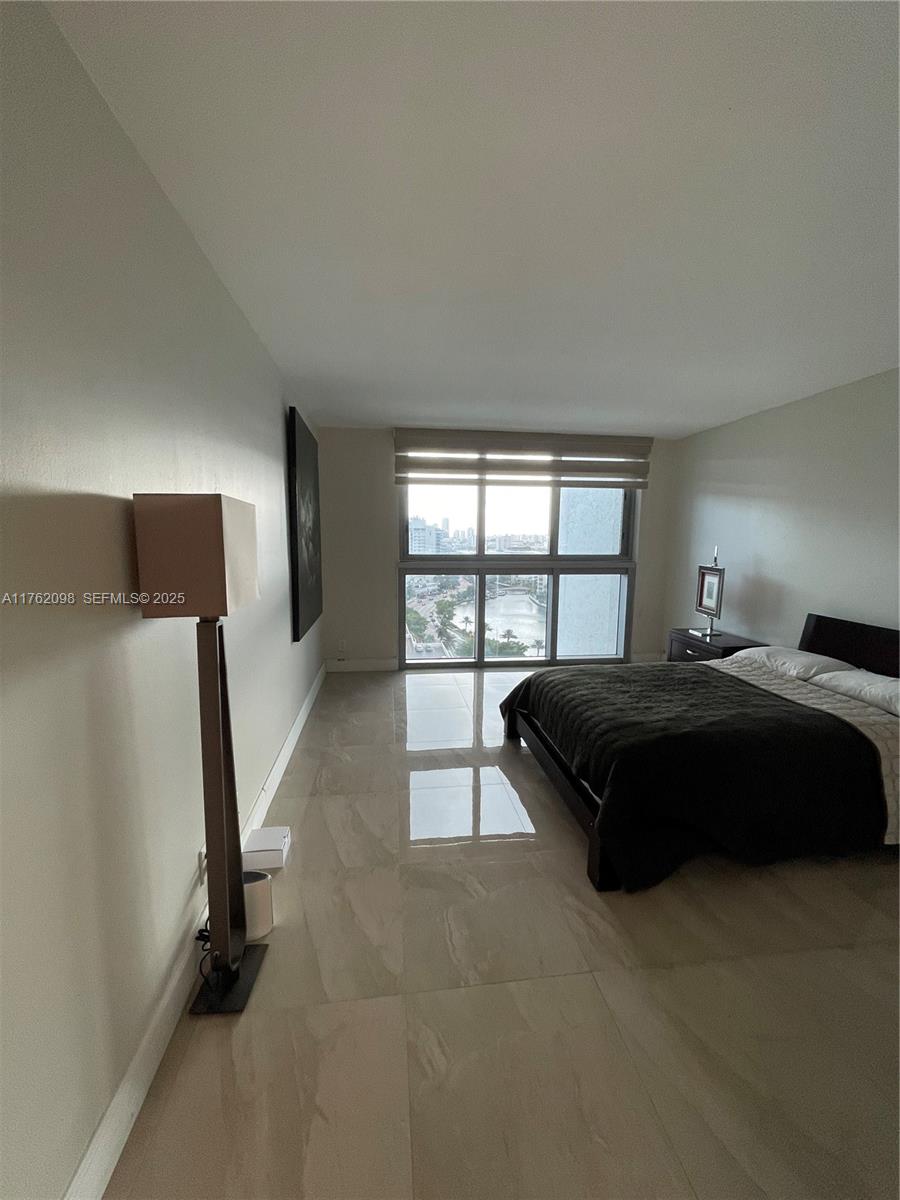 2655 Collins Avenue, Unit 1906 Miami Beach, FL 33140 - Photo 13 of 35 a spacious bedroom with a bed and a large window