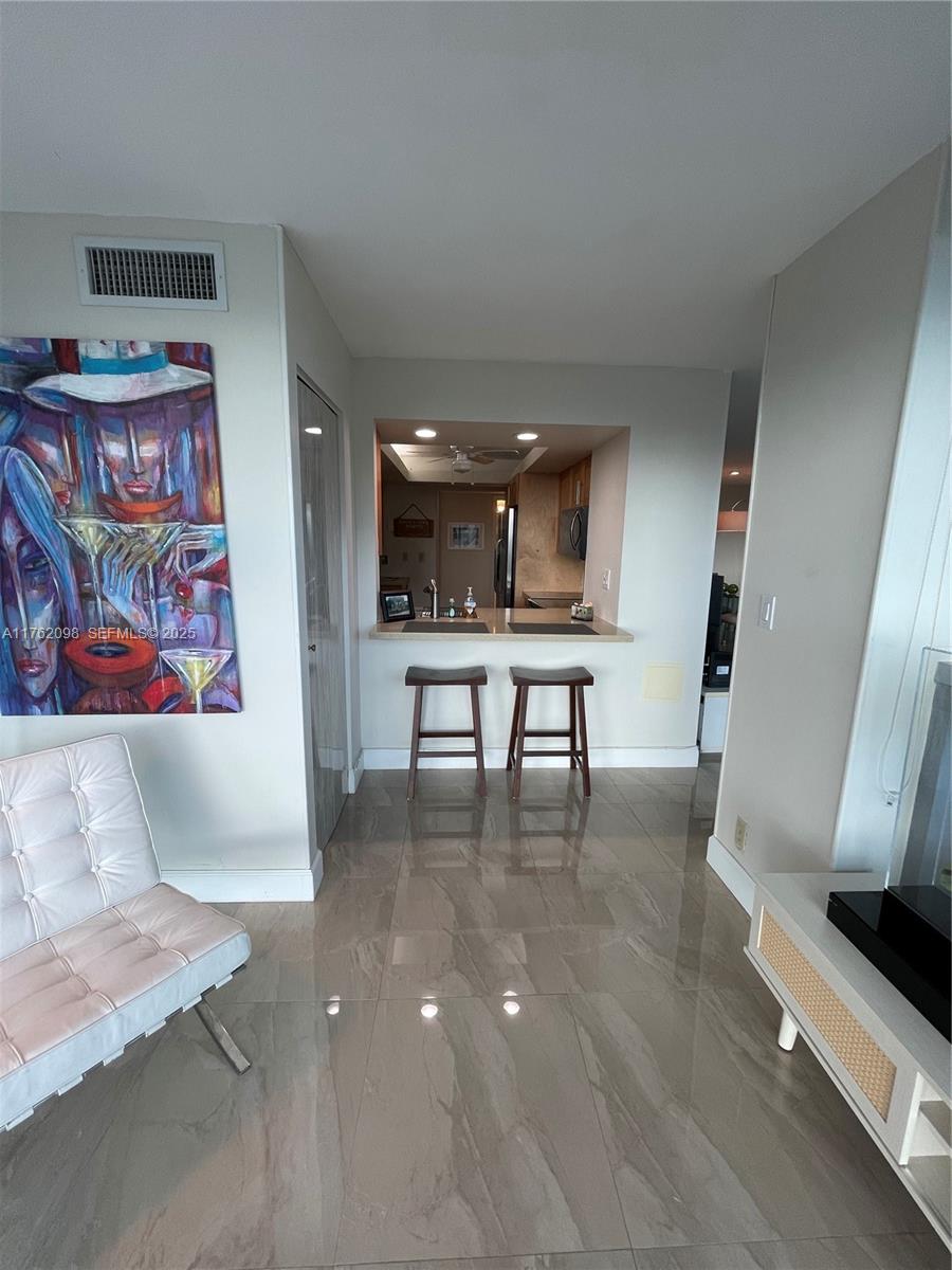 2655 Collins Avenue, Unit 1906 Miami Beach, FL 33140 - Photo 15 of 35 a view of kitchen with furniture and flat screen tv