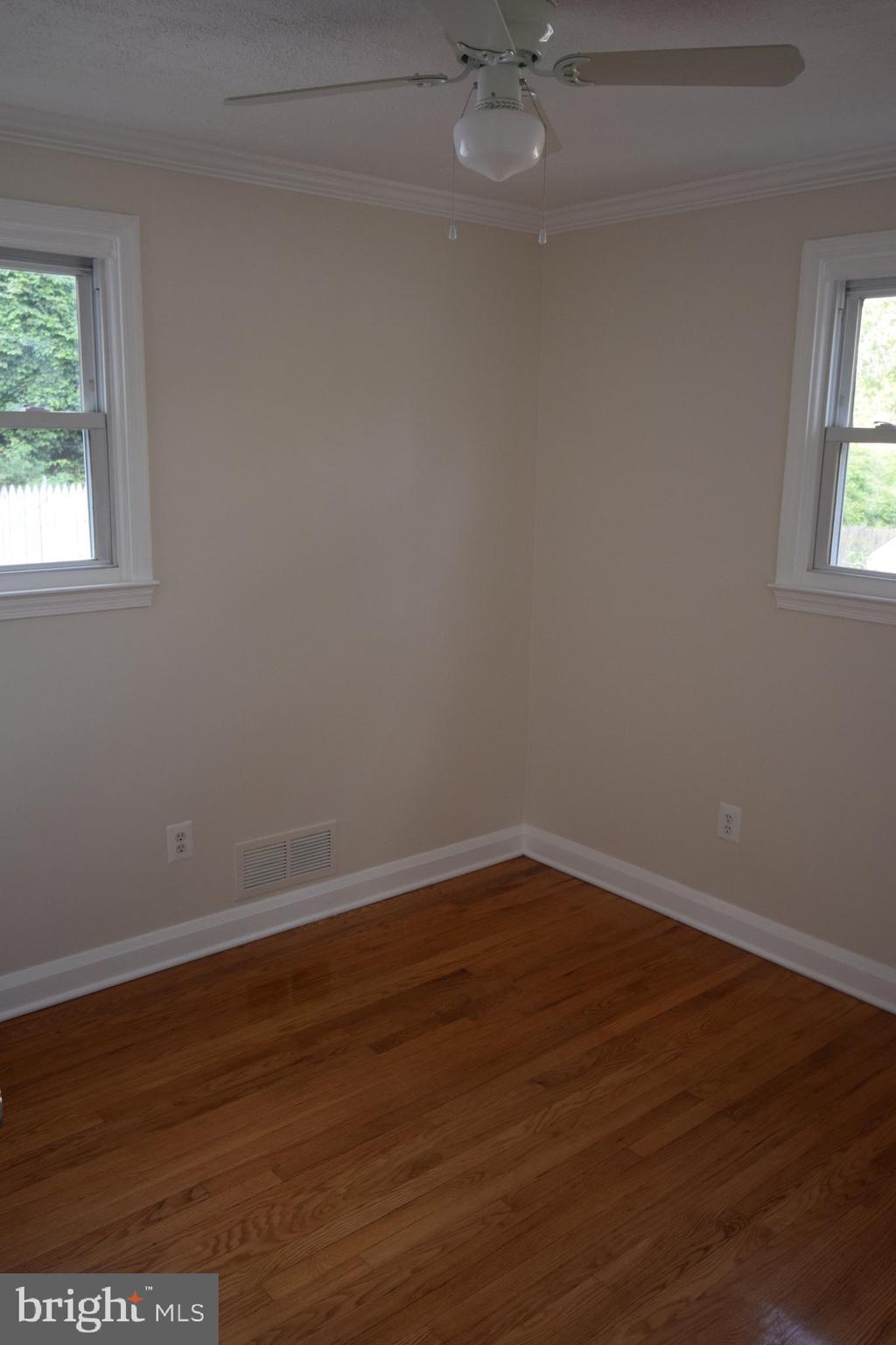 1354 Sudvale Road Pikesville, MD 21208 - Photo 7 of 17 an empty room with wooden floor and windows