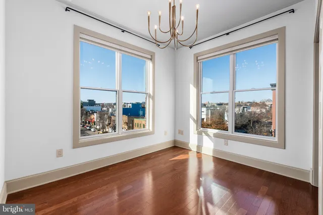 a view of a big room with wooden floor and windows