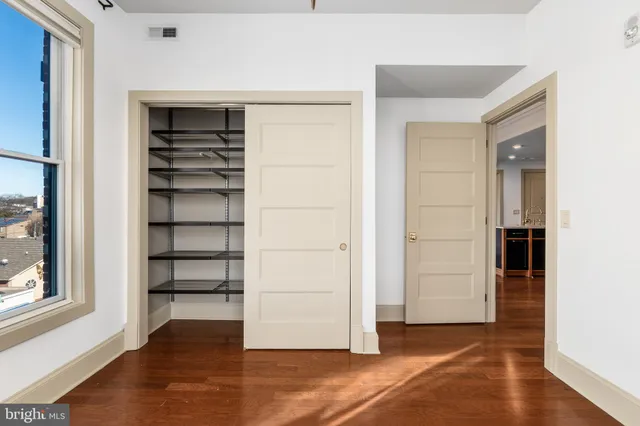 a view of a hallway with wooden floor and closet
