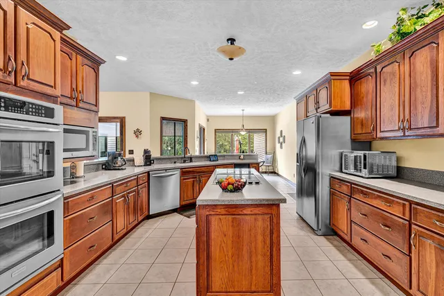 a kitchen with stainless steel appliances granite countertop a stove a sink dishwasher a refrigerator and cabinets with wooden floor