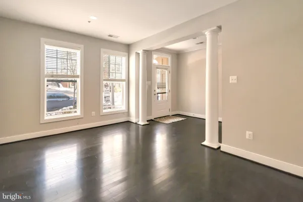 an empty room with wooden floor and windows with curtains