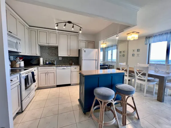 a kitchen with stainless steel appliances kitchen island granite countertop a table chairs and a refrigerator