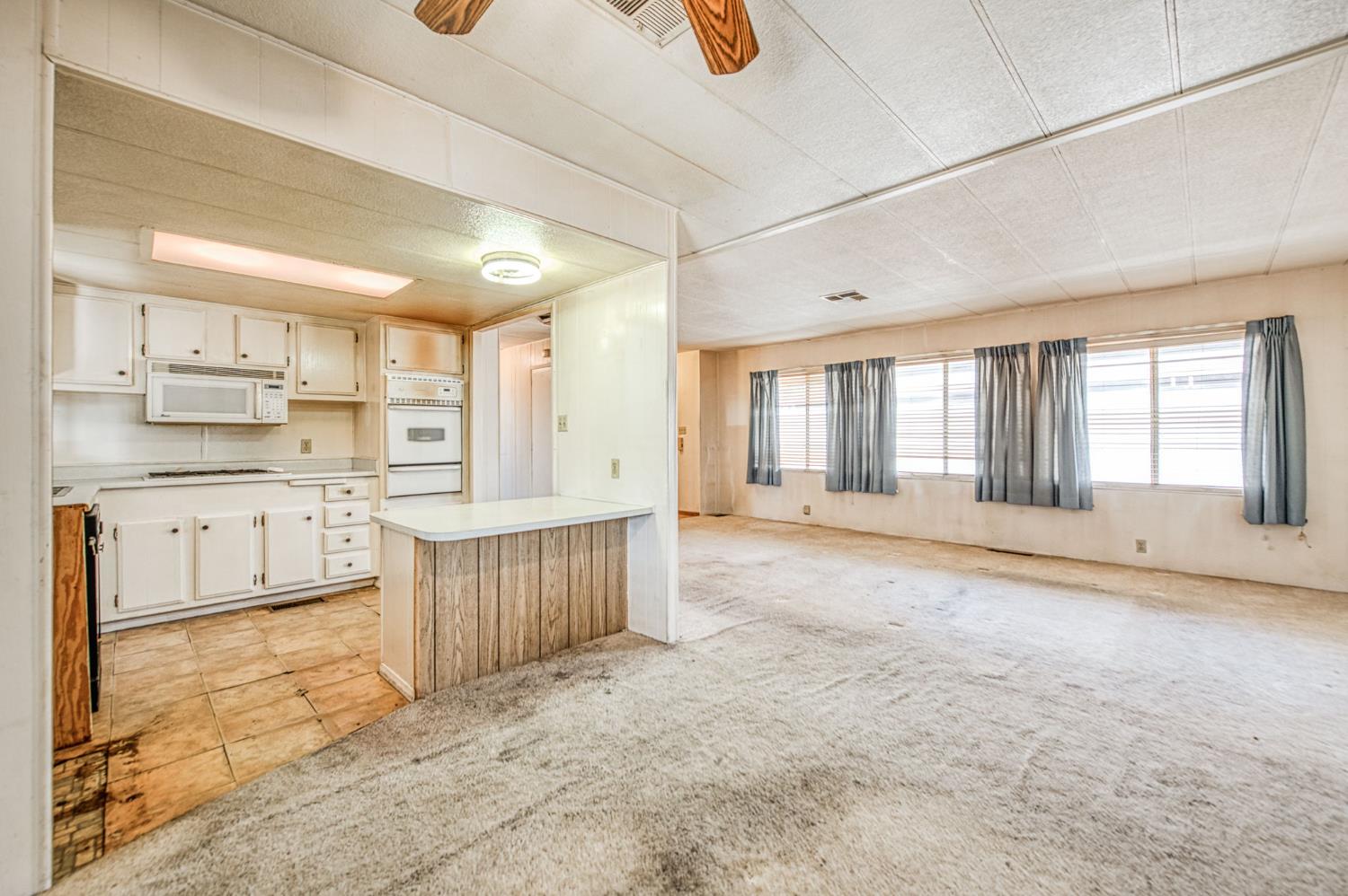 1300 West Olson Avenue, Unit 75 Reedley, CA 93654 - Photo 12 of 40 a large kitchen with kitchen island granite countertop a large window and white cabinets