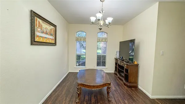 a dining room with wooden floor a chandelier a wooden table and chairs