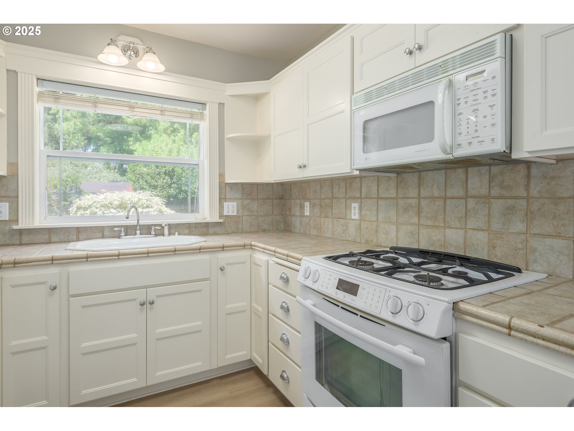 1507 Bogart Lane Eugene, OR 97401 - Photo 10 of 41 a kitchen with granite countertop a stove a sink dishwasher and white cabinets with wooden floor