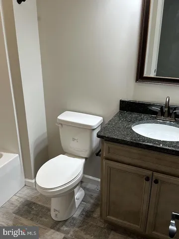 a bathroom with a granite countertop toilet sink and mirror
