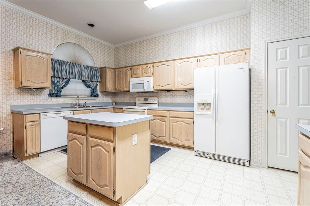 8317 Lake Bend Drive Rowlett, TX 75088 - Photo 10 of 35 Kitchen with white appliances, crown molding, a kitchen island, light flooring, and light countertops
