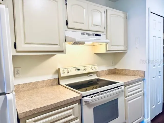 a kitchen with granite countertop white cabinets and white appliances