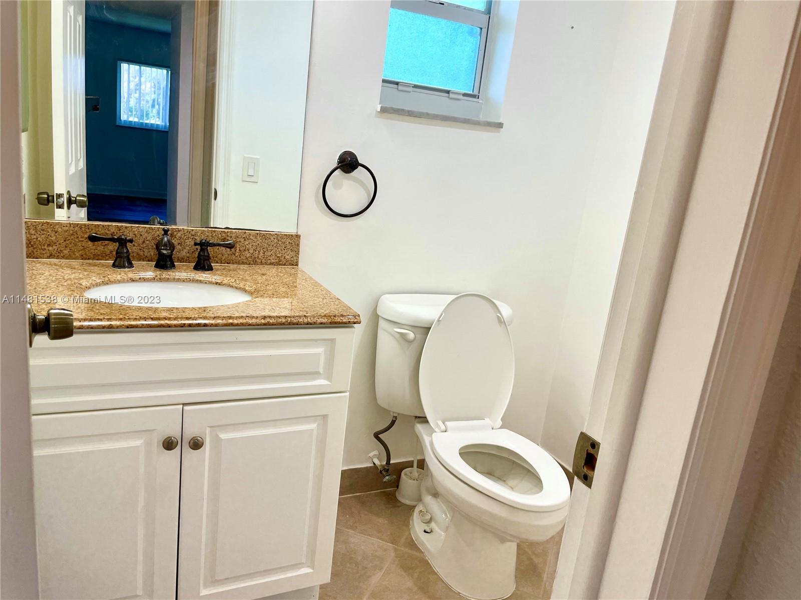 5100 Southwest 90th Avenue, Unit 303 Cooper City, FL 33328 - Photo 18 of 36 a bathroom with a granite countertop toilet sink and mirror