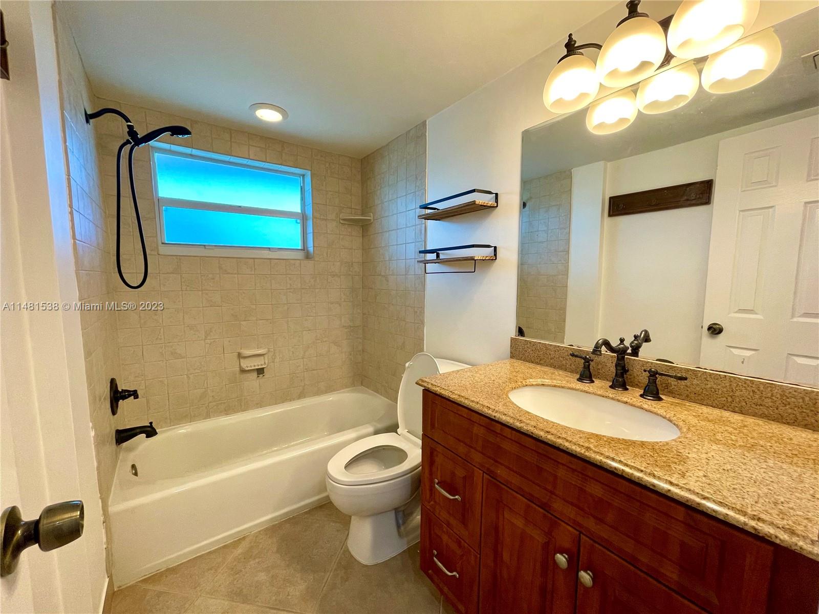 5100 Southwest 90th Avenue, Unit 303 Cooper City, FL 33328 - Photo 22 of 36 a bathroom with a granite countertop sink a toilet and bathtub