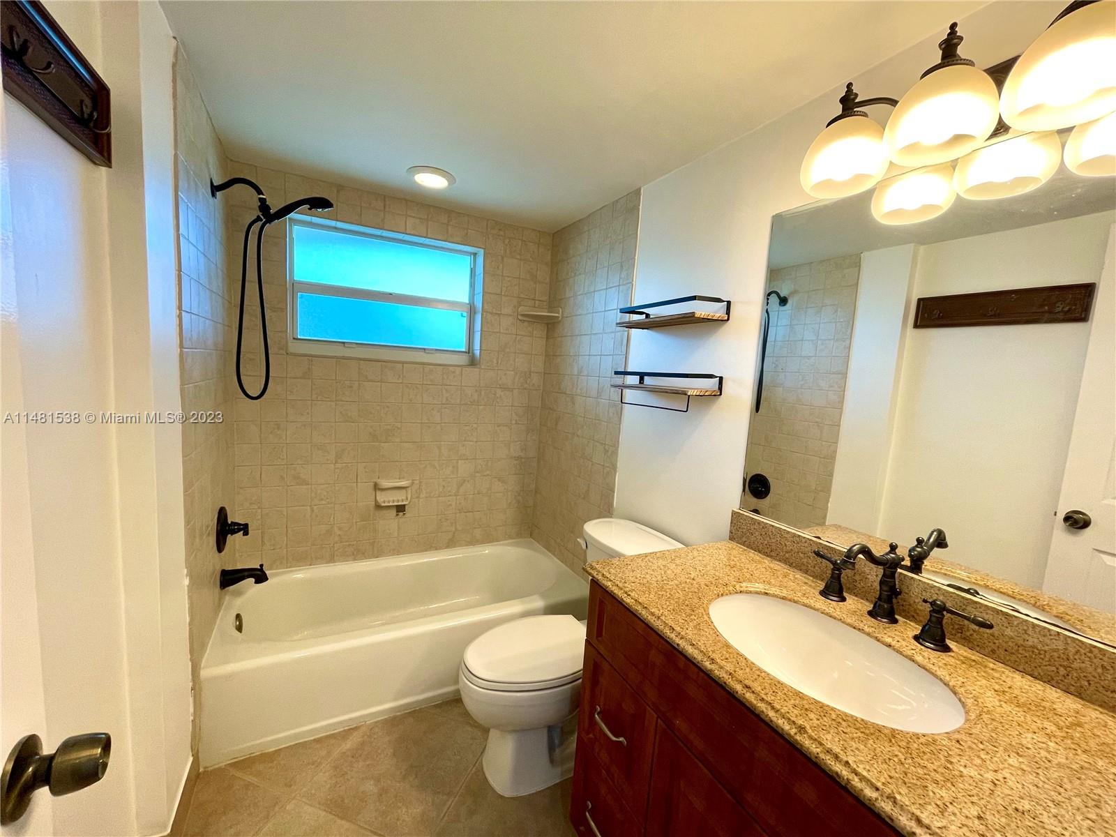 5100 Southwest 90th Avenue, Unit 303 Cooper City, FL 33328 - Photo 25 of 36 a bathroom with a granite countertop sink mirror toilet and bathtub