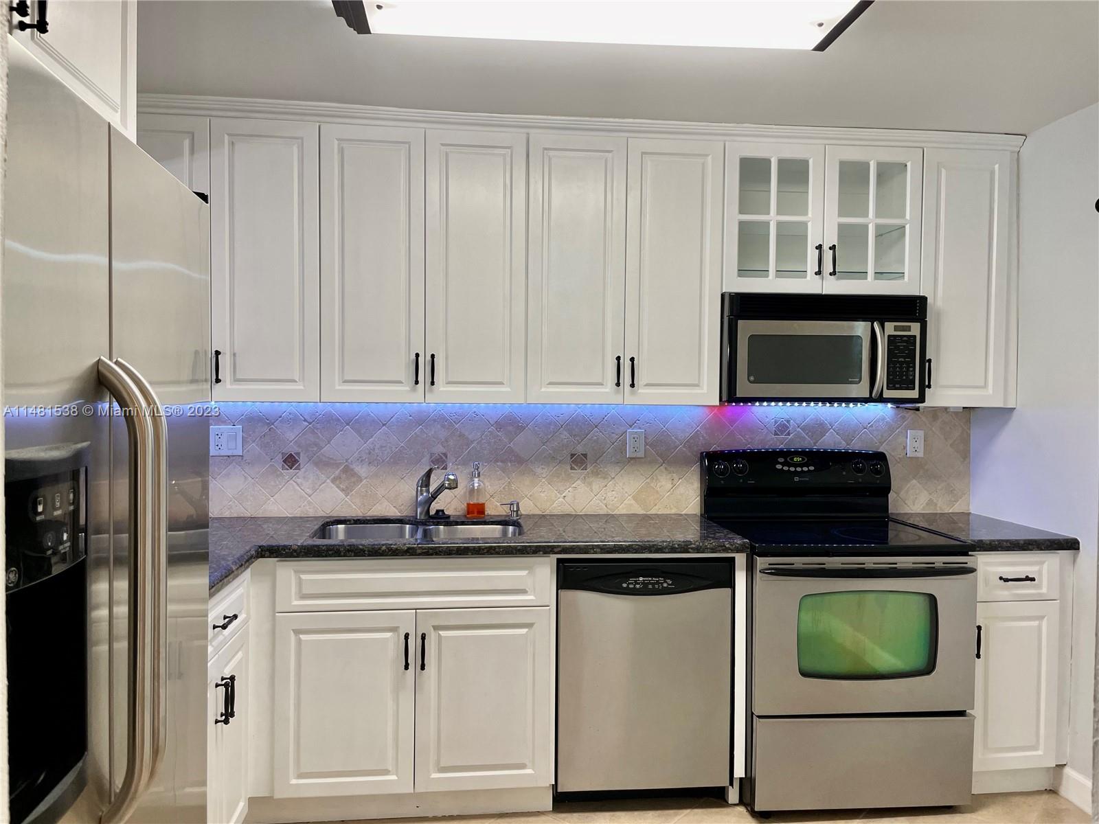 5100 Southwest 90th Avenue, Unit 303 Cooper City, FL 33328 - Photo 7 of 36 a kitchen with granite countertop white cabinets and black appliances