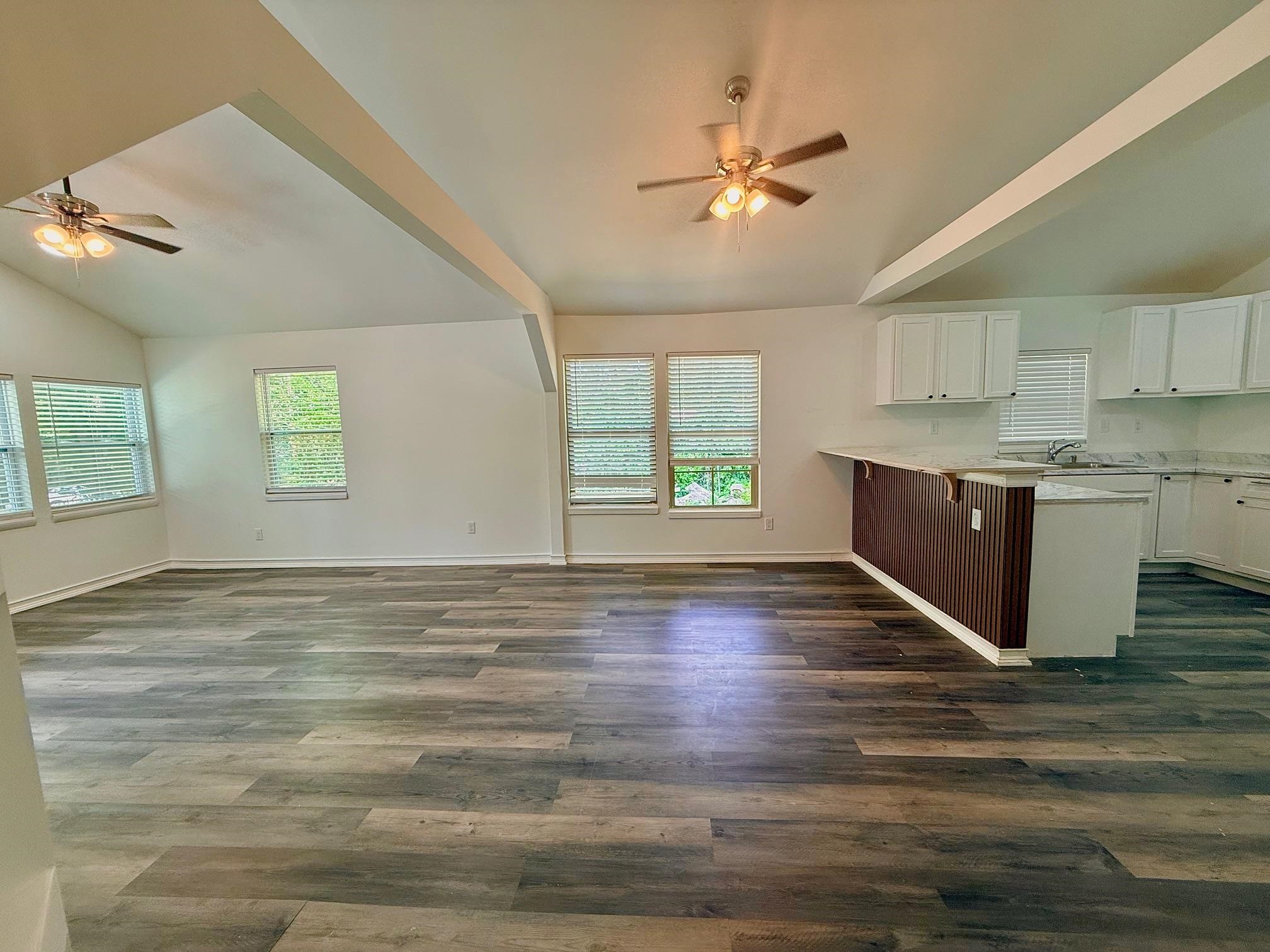 3054 Lotus Road Memphis, TN 38109 - Photo 5 of 29 Vaulted ceilings with exposed beams and ceiling fans, wood-finish flooring, white kitchen cabinetry, and a peninsula with a breakfast bar