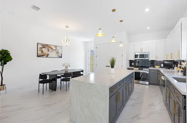 a large kitchen with kitchen island a sink a counter space and stainless steel appliances
