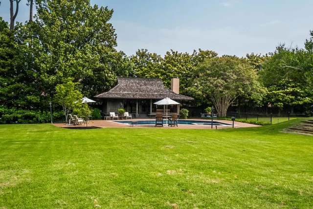 a view of a swimming pool with lawn chairs and plants
