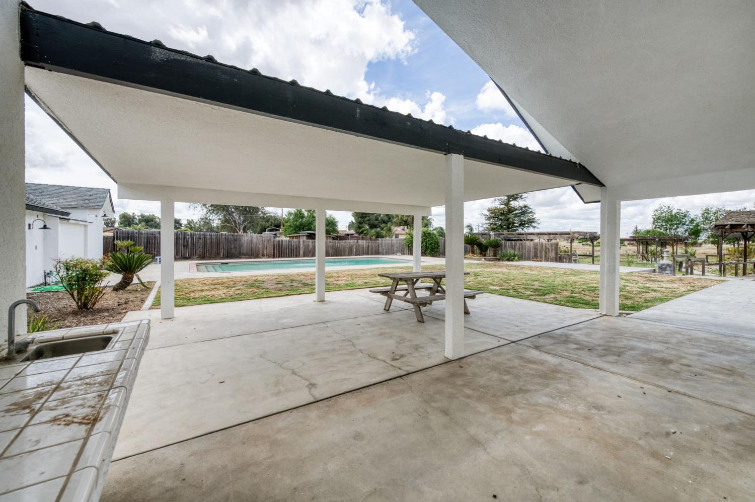 16564 Monreal Road Madera, CA 93636 - Photo 33 of 59 a view of a patio with a table and chairs under an umbrella next to a yard