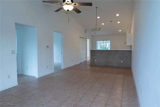 a view of an empty room with a chandelier fan