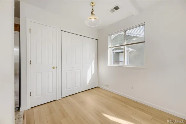 an empty room with wooden floor chandelier and windows