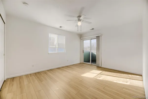an empty room with wooden floor and windows