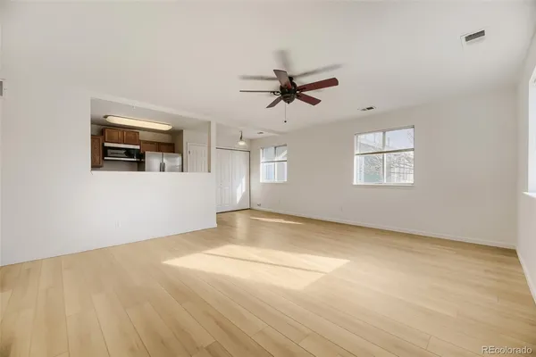 a view of empty room with wooden floor and ceiling fan
