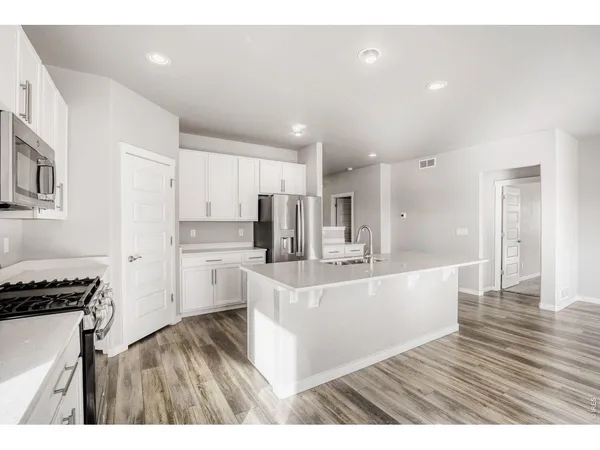 a living room with stainless steel appliances kitchen island a large counter top and white cabinets