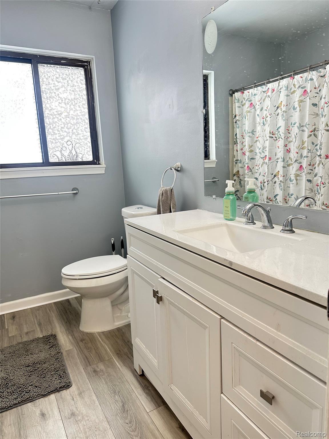 Full bath with vanity, light wood finished floors, and a bath/shower