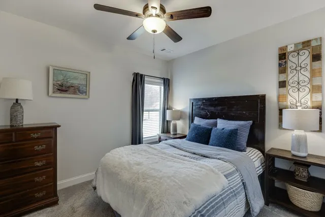 a bedroom with a bed and a lamp on dresser