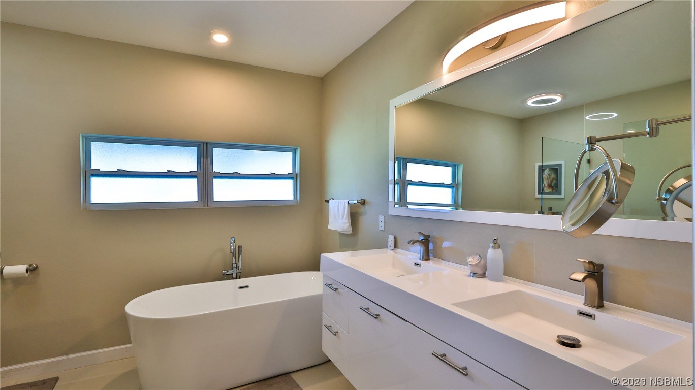 677 State Rte 415 New Smyrna Beach, FL 32168 - Photo 37 of 74 a bathroom with a double vanity sink mirror and bathtub