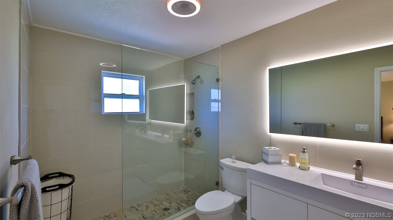 677 State Rte 415 New Smyrna Beach, FL 32168 - Photo 40 of 74 a bathroom with a granite countertop sink a toilet and shower