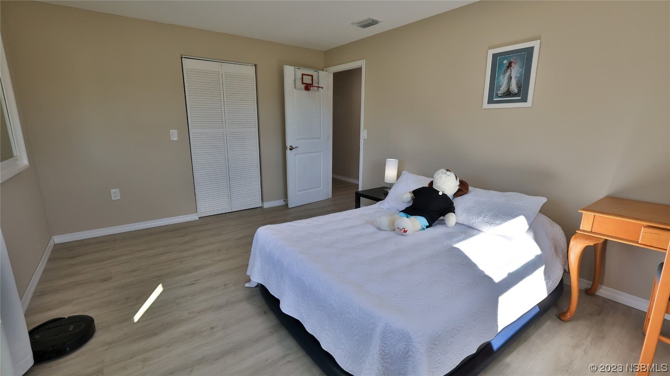 677 State Rte 415 New Smyrna Beach, FL 32168 - Photo 42 of 74 a bedroom with a bed and wooden floor