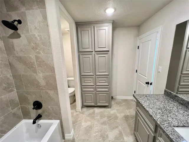 a bathroom with a granite countertop sink a vanity and shower