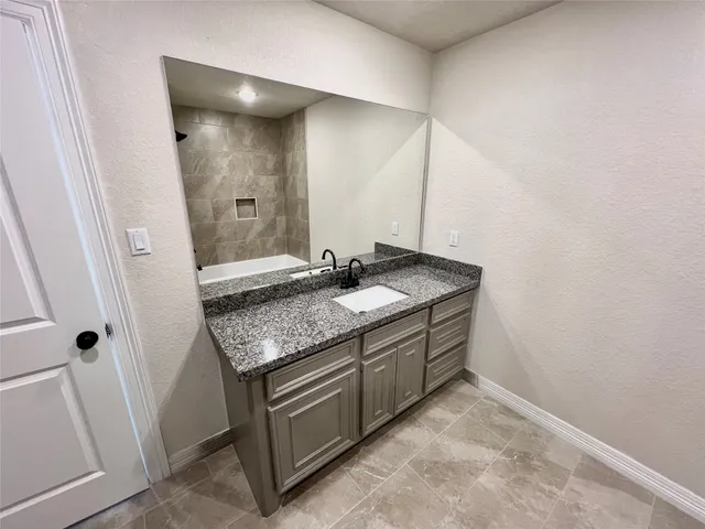 a bathroom with a granite countertop sink and a mirror