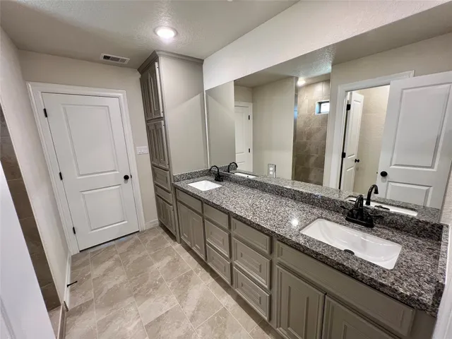 a bathroom with a granite countertop double vanity sink and a mirror