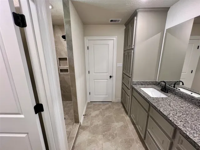 a bathroom with a granite countertop sink and mirror with shower