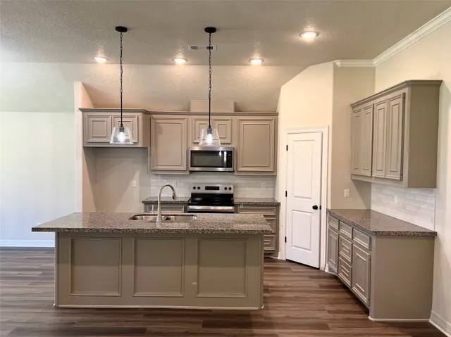 a kitchen with kitchen island granite countertop a sink cabinets and stainless steel appliances