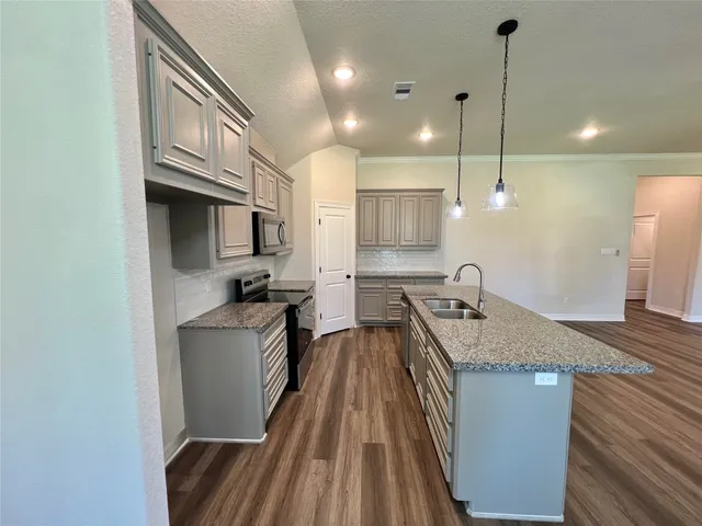 a kitchen with kitchen island granite countertop a sink a counter space appliances and cabinets
