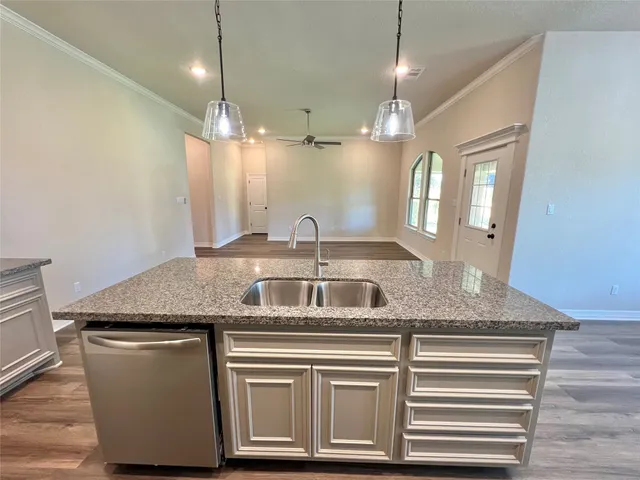 a kitchen with a granite countertop sink a counter top space and cabinets