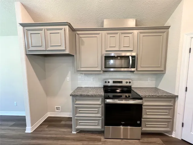 a kitchen with granite countertop white cabinets and black appliances