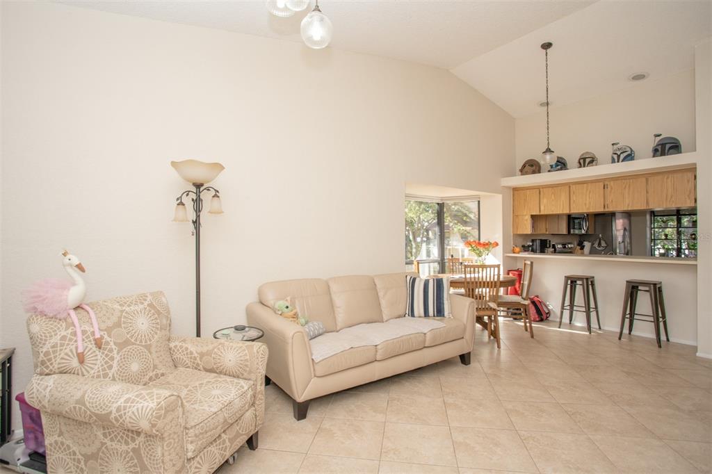 11511 113th Street, Unit 13H Largo, FL 33778 - Photo 9 of 28 a living room with furniture a chandelier and kitchen view