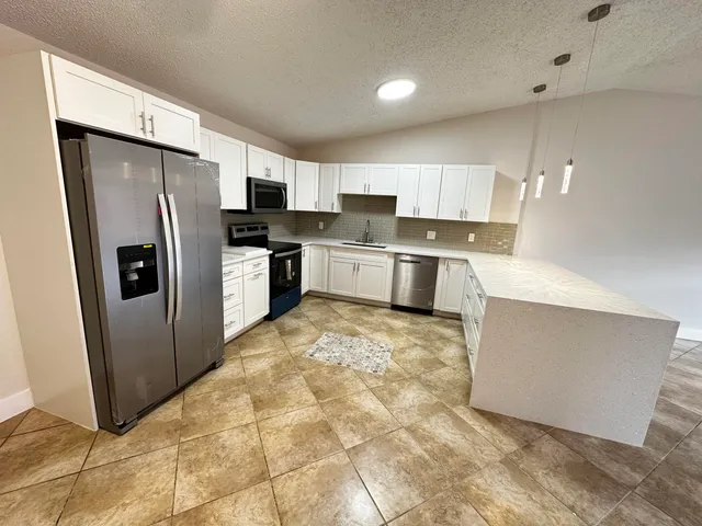 a kitchen with stainless steel appliances a refrigerator sink and microwave