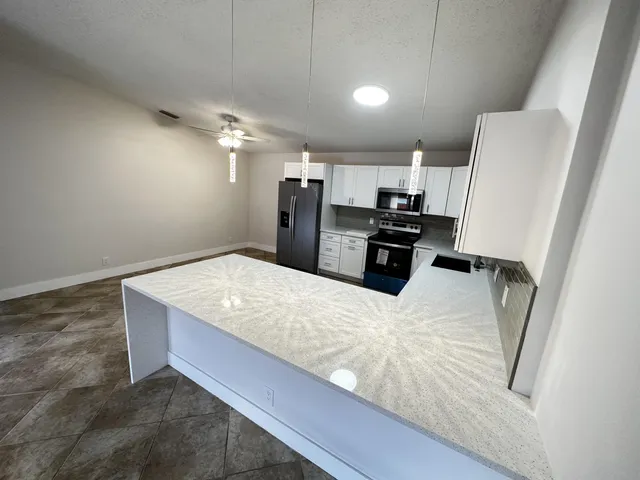 a kitchen with kitchen island sink stove and refrigerator