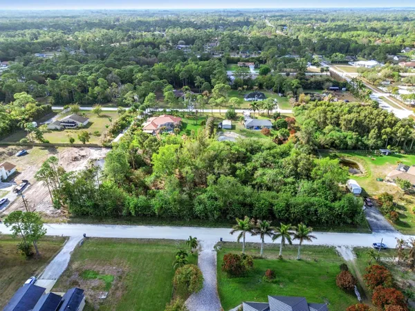 an aerial view of residential houses with outdoor space and trees all around