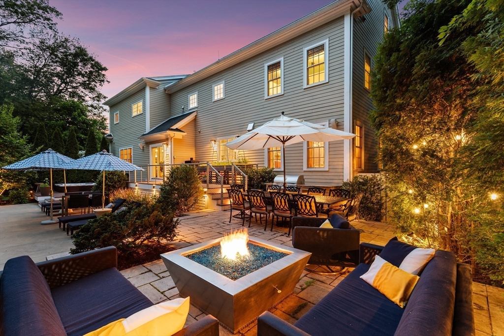 12 Cooke Road Lexington, MA 02420 - Photo 42 of 42 a view of a patio with couches table and chairs under an umbrella with a barbeque